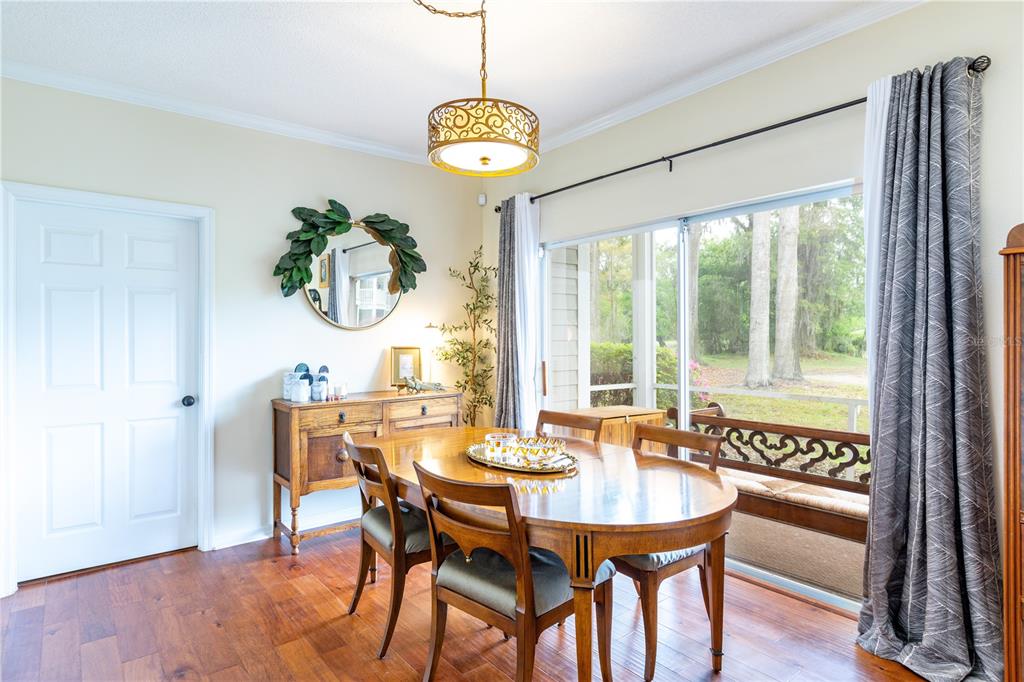 A dining room features a wooden table, chairs, a sideboard, and large windows with curtains — 10000 SW 52ND AVENUE UNIT 124, GAINESVILLE, FL