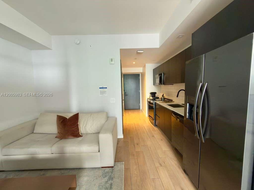 A modern apartment features a white sofa next to a kitchen with dark cabinets — 398 NE 5th St # 4313, Miami FL 33132, MIAMI, FL