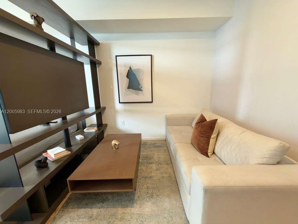 A living room features a light-colored sofa, a wooden coffee table, and a dark shelving unit — 398 NE 5th St # 4313, Miami FL 33132, MIAMI, FL