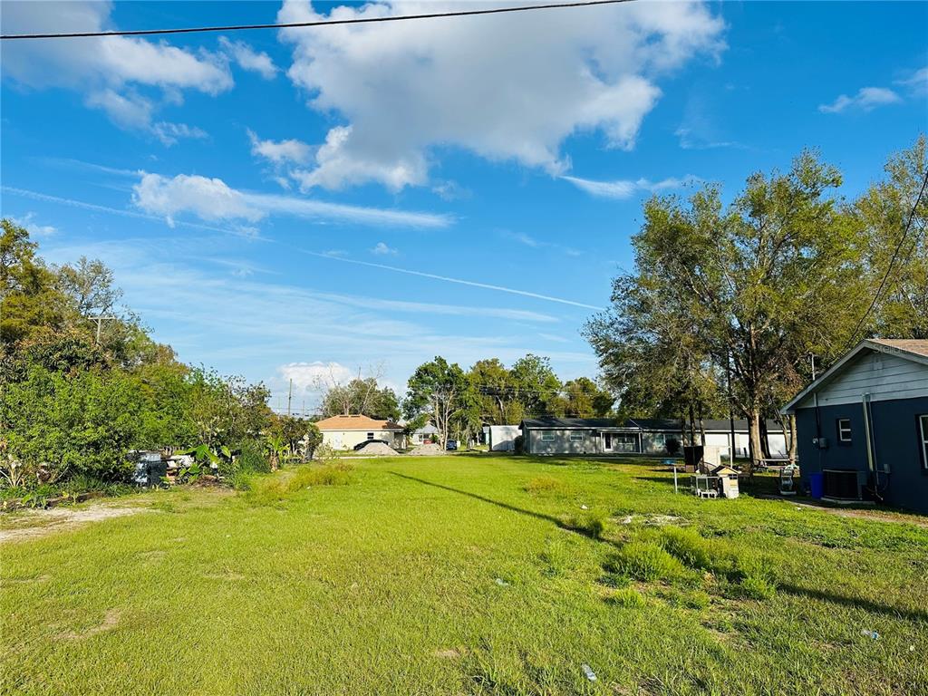 A grassy vacant lot sits between two residential buildings under a blue sky — 0 RAILROAD AVENUE, FORT MEADE, FL