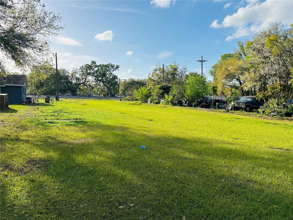 A large, grassy vacant lot features scattered trees, a small shed, and a parked truck — 0 RAILROAD AVENUE, FORT MEADE, FL
