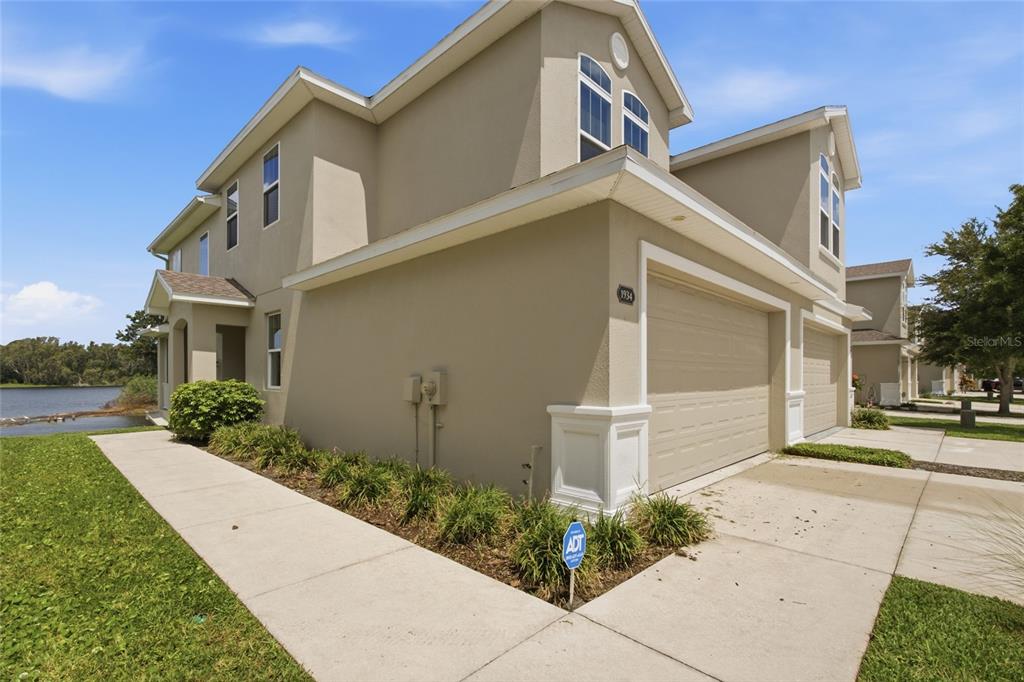 A beige two-story townhouse with a two-car garage sits next to a lake — 1934 LAKE RIDGE BOULEVARD, CLEARWATER, FL