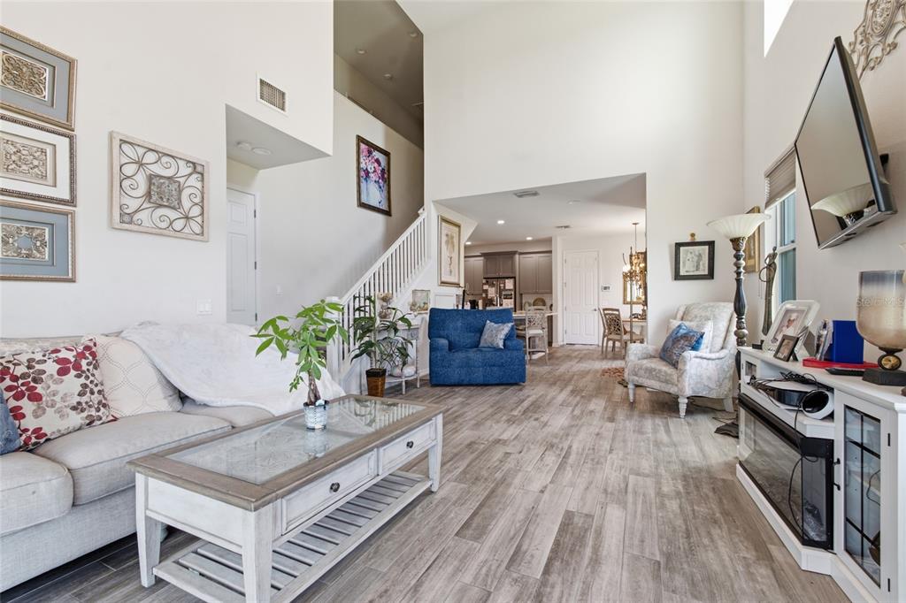 A living room with wood-look tile flooring, a high ceiling, and a staircase — 1934 LAKE RIDGE BOULEVARD, CLEARWATER, FL