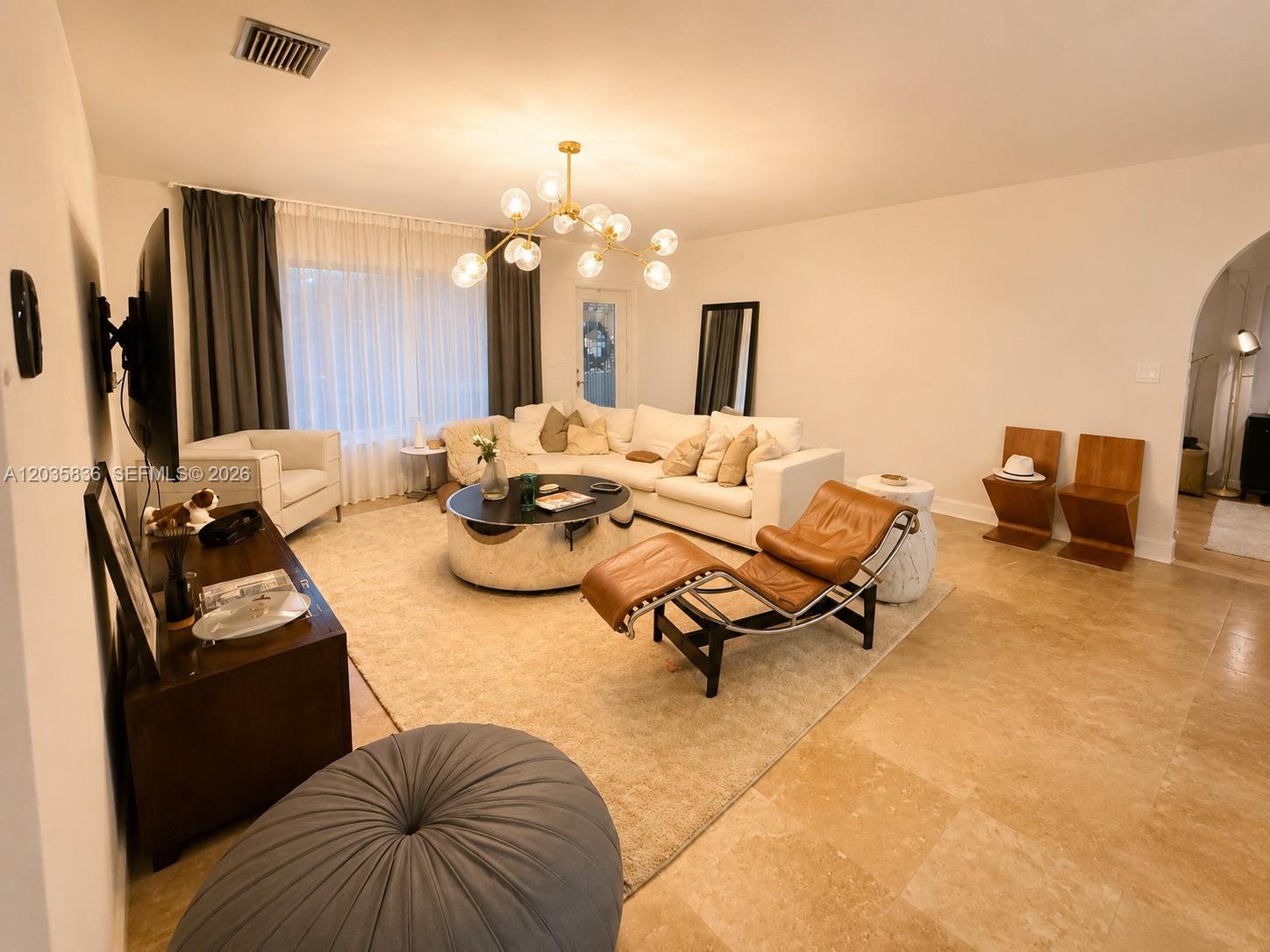 A living room features a white sectional sofa, a leather lounge chair, and a chandelier — 1183 NE 88th St, Miami FL 33138, MIAMI, FL