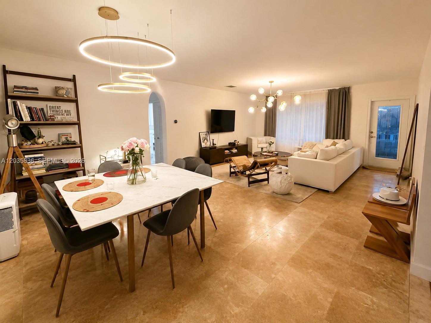 An open-concept living and dining area features tile flooring, modern lighting, and neutral furnishings — 1183 NE 88th St, Miami FL 33138, MIAMI, FL