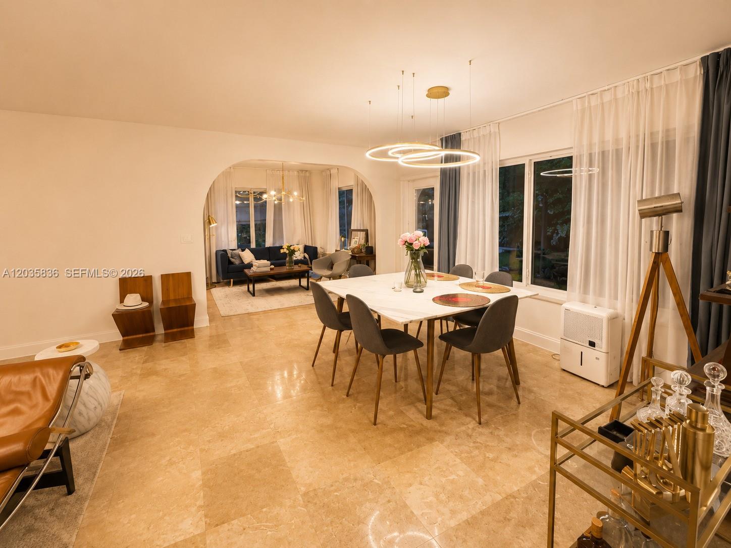 A dining area with a marble table and modern lighting opens into a living room — 1183 NE 88th St, Miami FL 33138, MIAMI, FL