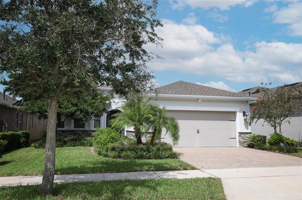 A single-story house with a beige garage, stone accents, and a palm tree in front — 560 ADENMORE TERRACE, DELAND, FL