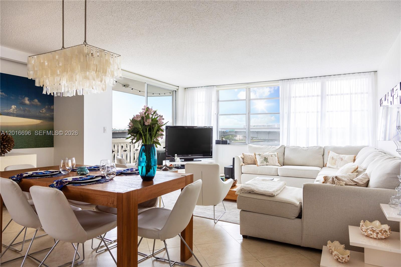 A bright living and dining area features a wooden table, white sectional, and large windows — 1817 S Ocean Dr # 320, Hallandale Beach FL 33009, HALLANDALE BEACH, FL