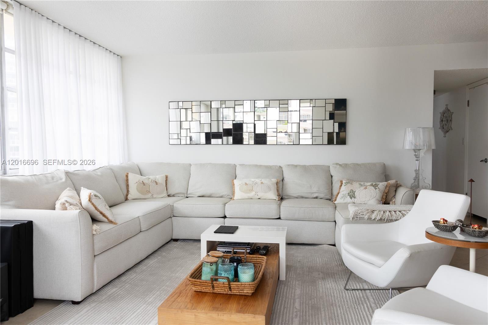 A living room features a large sectional sofa, a coffee table, and a decorative wall mirror — 1817 S Ocean Dr # 320, Hallandale Beach FL 33009, HALLANDALE BEACH, FL