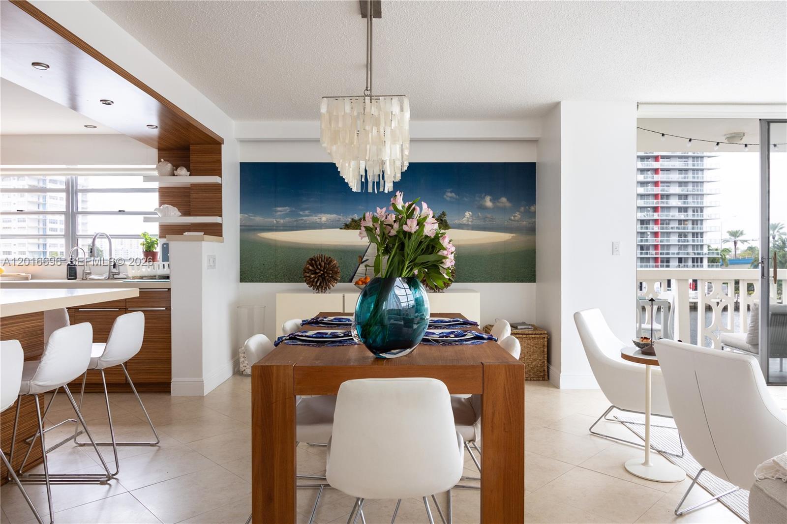 A dining area features a wooden table, white chairs, a chandelier, and a large wall mural — 1817 S Ocean Dr # 320, Hallandale Beach FL 33009, HALLANDALE BEACH, FL