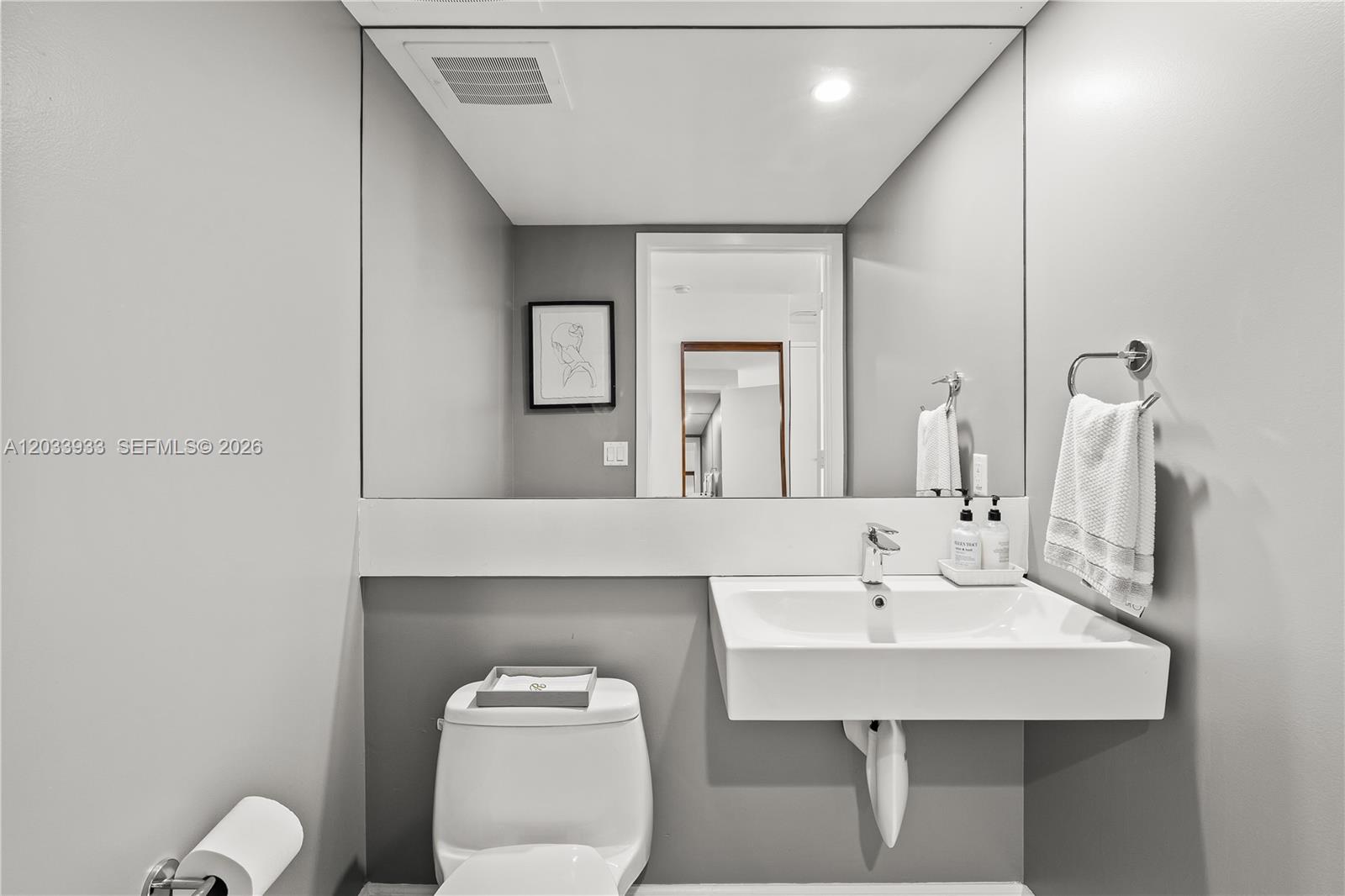 A modern bathroom features a wall-mounted sink, a large mirror, and a white toilet — 901 BRICKELL KEY BL # 2206, Miami FL 33131, MIAMI, FL