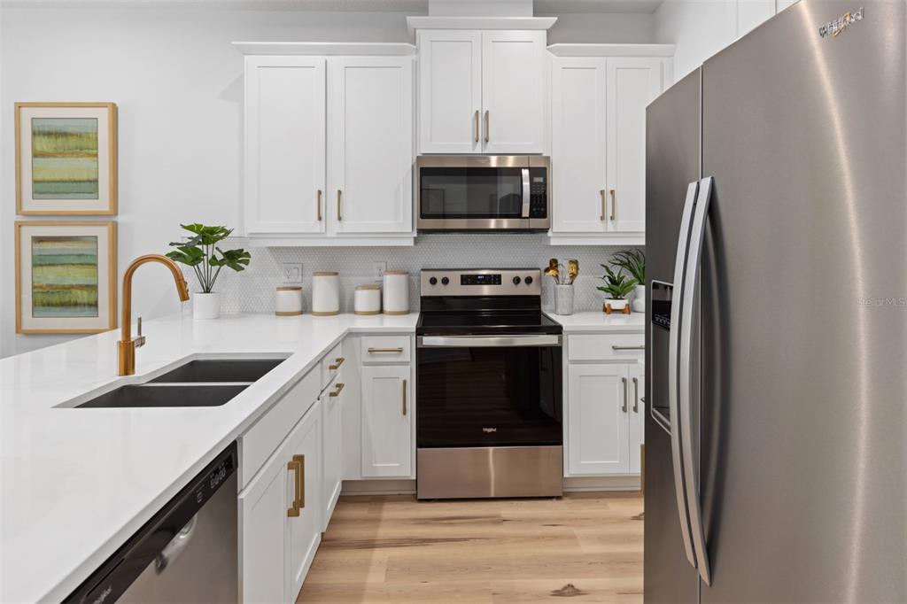 A modern kitchen features white cabinets, stainless steel appliances, and a white quartz countertop — 1407 TARFLOWER DRIVE, WINTER SPRINGS, FL