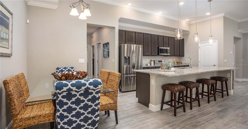 A kitchen with dark cabinets and a granite island sits beside a dining area — 902 BUCKEYE DRIVE, LADY LAKE, FL