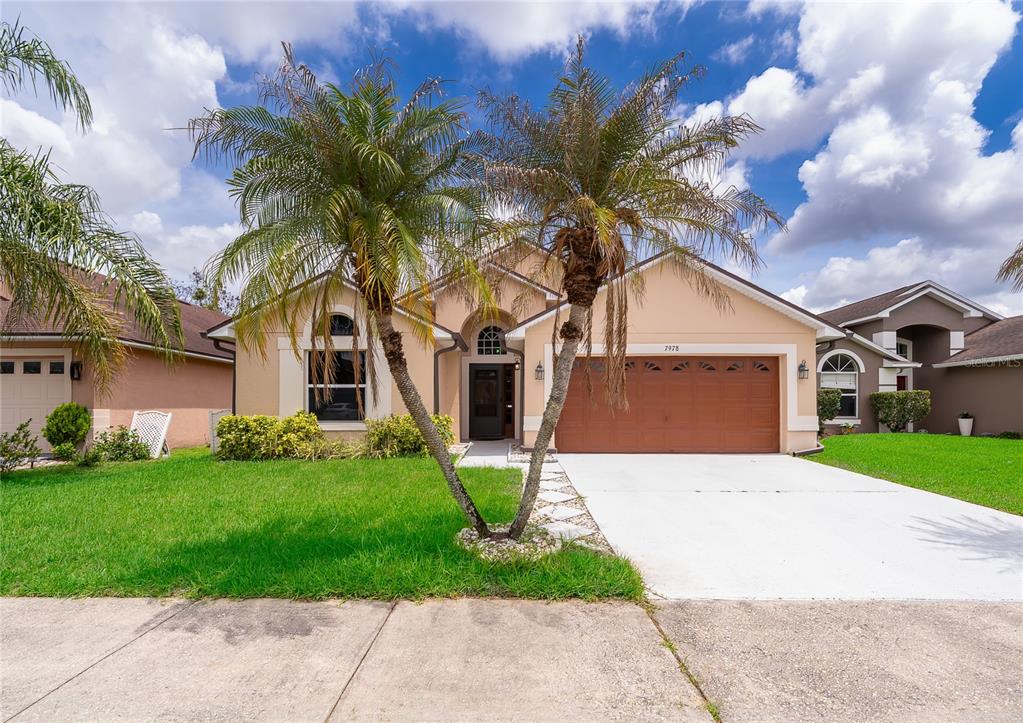 A single-story suburban house with a two-car garage, palm trees, and a concrete driveway — 7978 ELMSTONE CIRCLE, ORLANDO, FL