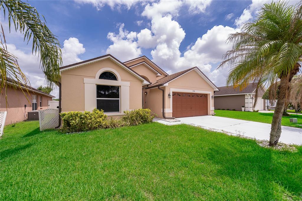 A single-story tan house with a brown garage door and a palm tree in front — 7978 ELMSTONE CIRCLE, ORLANDO, FL