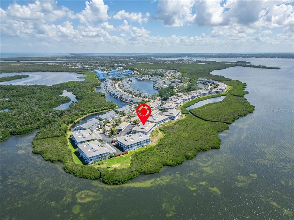 An aerial view shows a multi-story residential complex surrounded by water and dense vegetation — 1343 PERICO POINT CIRCLE UNIT 117, BRADENTON, FL