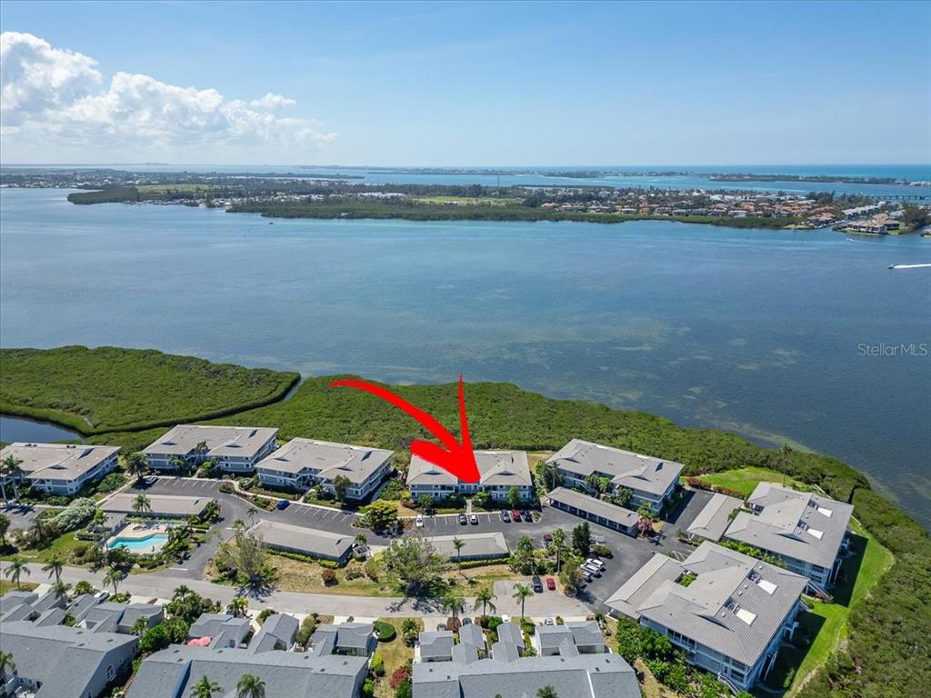An aerial view shows a multi-story residential complex situated along a waterfront with mangroves — 1343 PERICO POINT CIRCLE UNIT 117, BRADENTON, FL