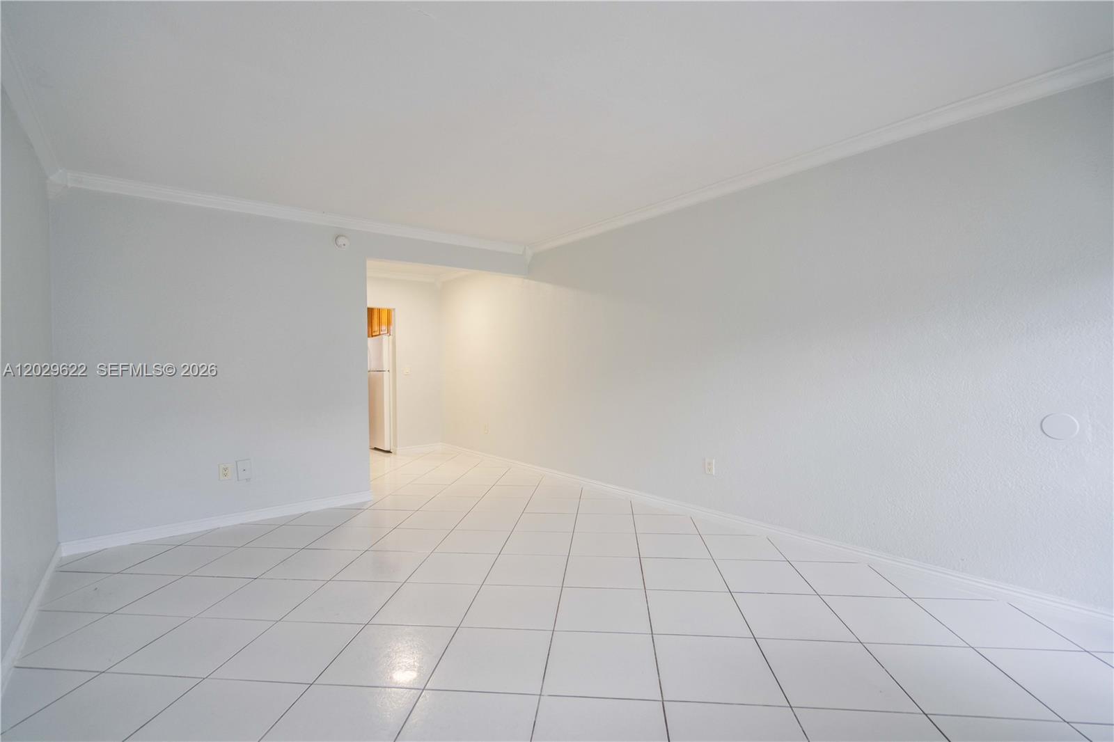 An empty room features white walls, crown molding, and white tiled flooring — 7640 Carlyle Ave # 9B, Miami Beach FL 33141, MIAMI BEACH, FL