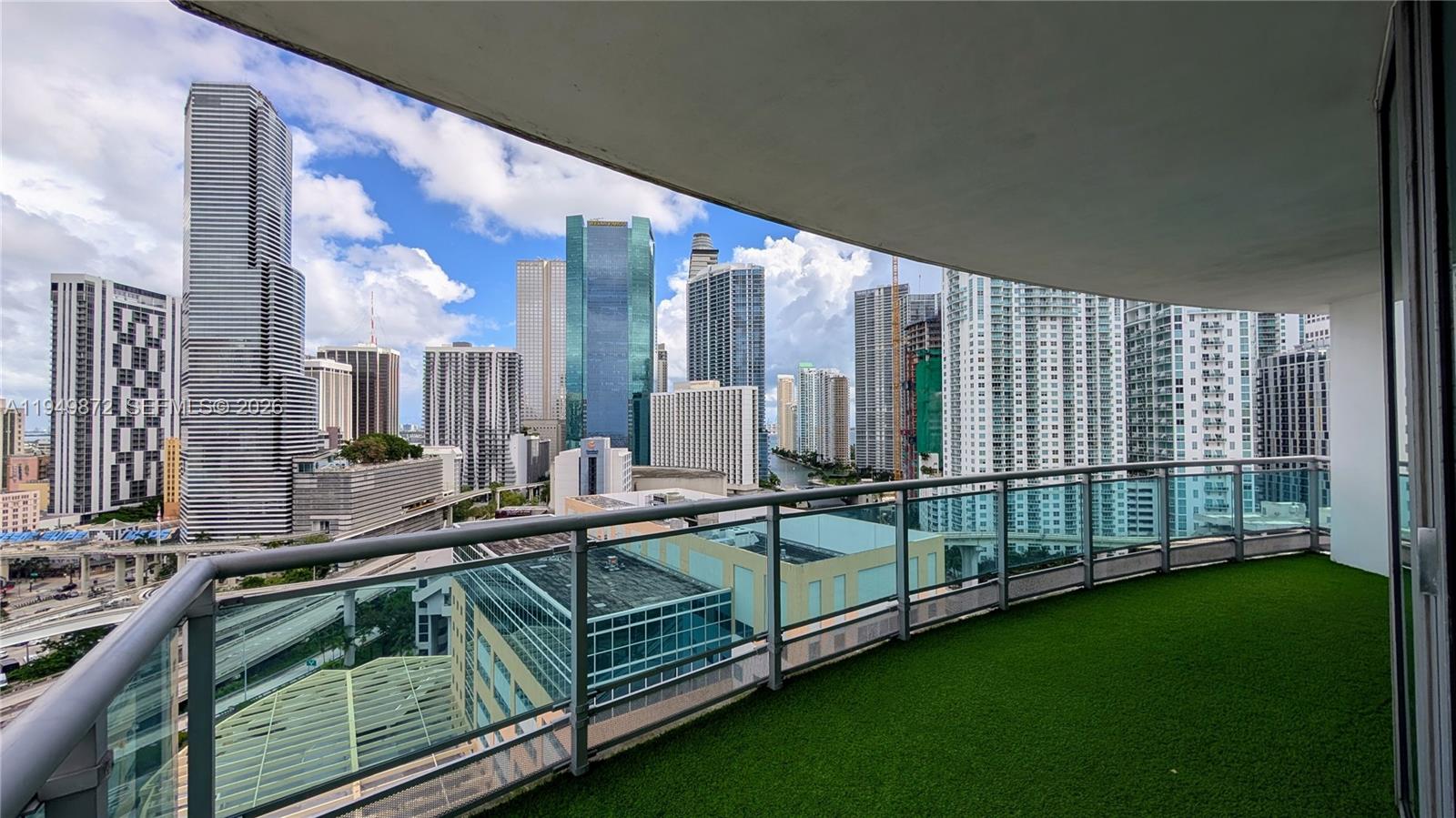 A balcony with artificial turf flooring overlooks a dense urban skyline of high-rise buildings — 350 S Miami Ave # 1901, Miami FL 33130, MIAMI, FL