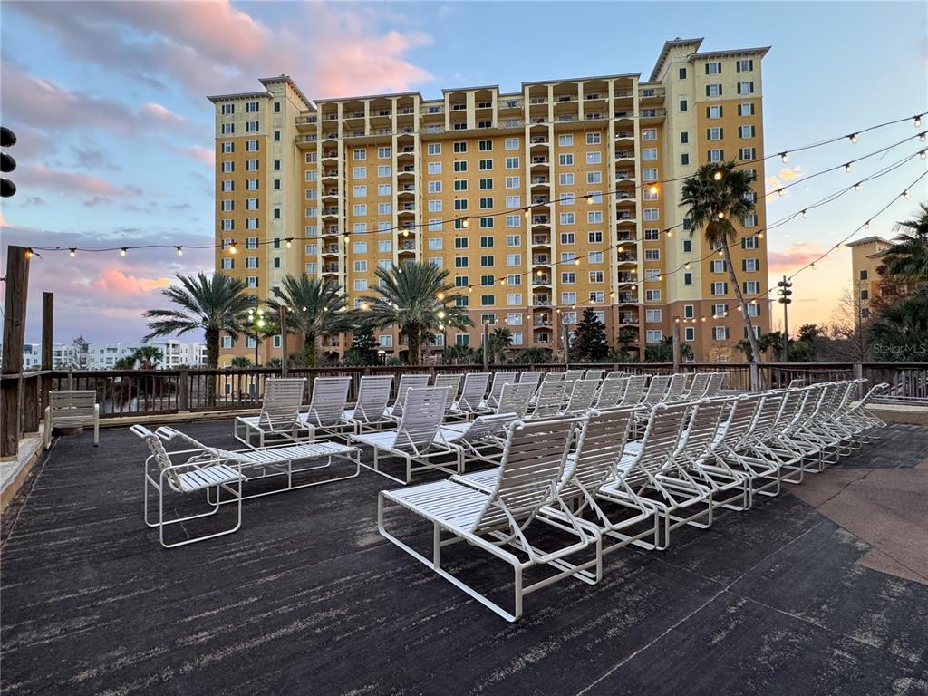 A large outdoor deck features many white lounge chairs facing a tall, yellow apartment building — 8125 RESORT VILLAGE DRIVE UNIT 5304, ORLANDO, FL