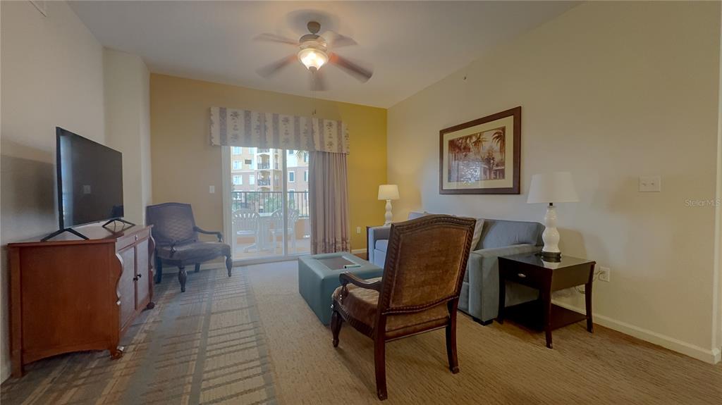 A living room features a sofa, two armchairs, a television, and a sliding glass door — 8125 RESORT VILLAGE DRIVE UNIT 5304, ORLANDO, FL