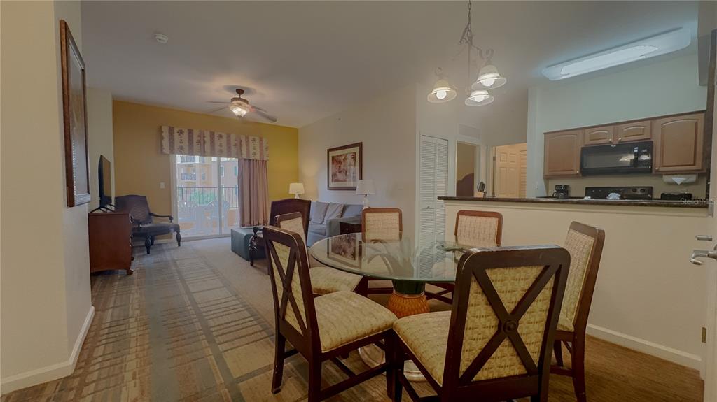 A dining area with a glass table sits in front of a kitchen and living room — 8125 RESORT VILLAGE DRIVE UNIT 5304, ORLANDO, FL