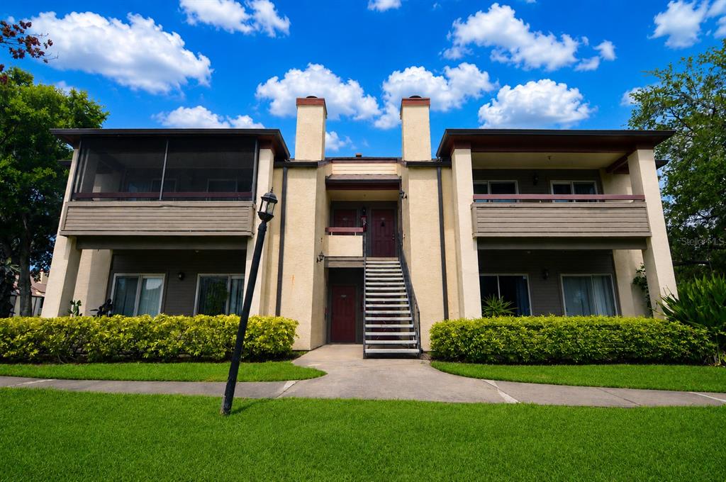 A two-story apartment building with a central staircase, balconies, and a landscaped lawn — 10263 GANDY BOULEVARD N UNIT 2116, ST PETERSBURG, FL