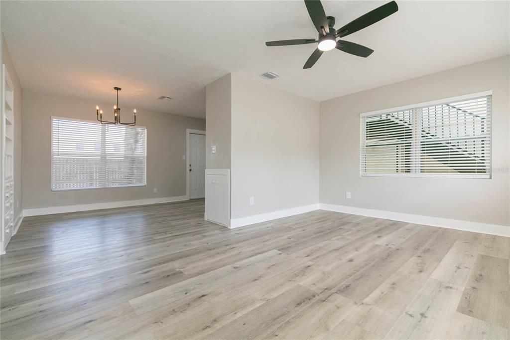 A bright living room features light wood-look flooring, a ceiling fan, and two large windows — 2600 52ND AVENUE N UNIT B, ST PETERSBURG, FL
