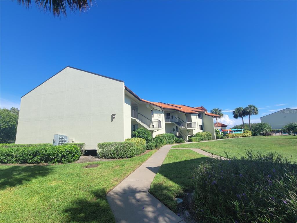 A two-story apartment building with a sidewalk leading to the entrance under a clear sky — 1515 PINELLAS BAYWAY S UNIT 62, TIERRA VERDE, FL