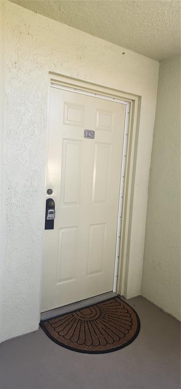 A white exterior door with a lockbox and a semi-circular doormat at the entrance — 1515 PINELLAS BAYWAY S UNIT 62, TIERRA VERDE, FL