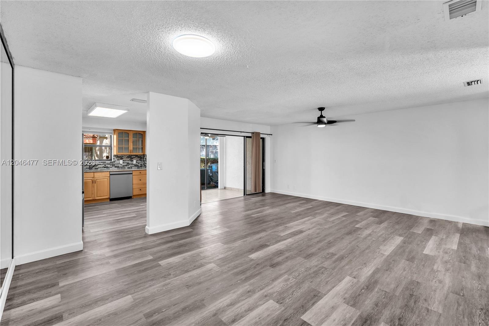 An open-concept living area features wood-look flooring, a ceiling fan, and an adjacent kitchen — 3405 Emerald Oaks Dr # 207, Hollywood FL 33021, HOLLYWOOD, FL