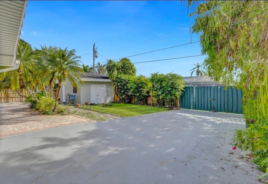 A paved driveway leads to a small shed, a grassy yard, and a green fence — 5500 Buchanan St, Hollywood FL 33021, HOLLYWOOD, FL