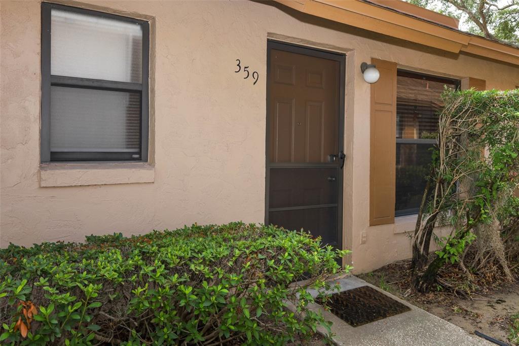 The exterior of a tan residential unit features a front door numbered 359 — 359 DOUGLAS WAY UNIT 54, WINTER GARDEN, FL