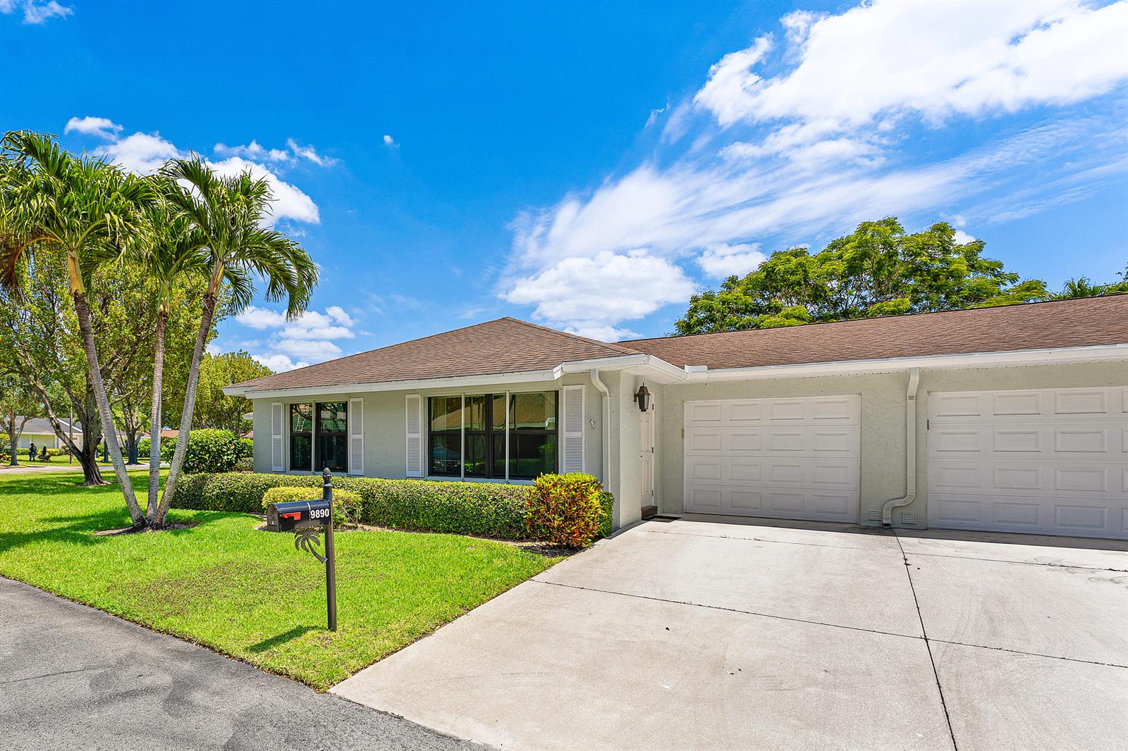 A single-story house with a concrete driveway, two garage doors, and palm trees in front — 9890 Papaya Tree Trail # A, Boynton Beach FL 33436, BOYNTON BEACH, FL