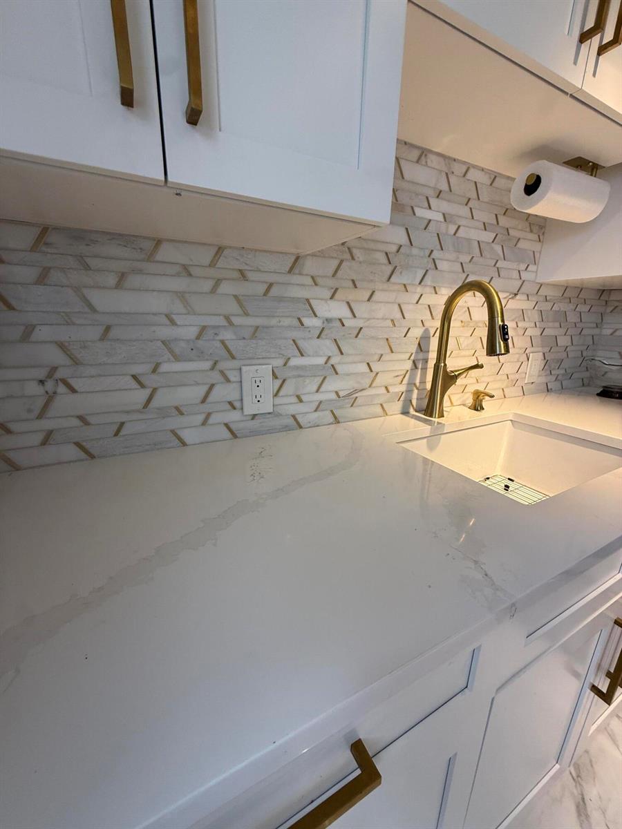 A kitchen sink area features white quartz countertops, a gold faucet, and a patterned backsplash — 389 Fanshaw J # 389, Boca Raton FL 33434, BOCA RATON, FL