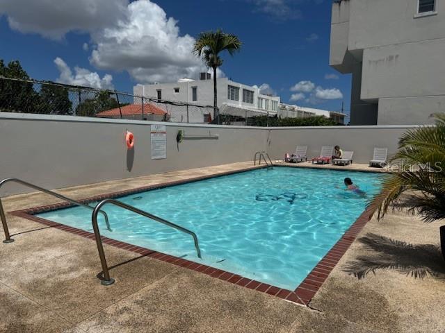 An outdoor swimming pool is surrounded by a concrete deck and a white wall — Ave. 50 A COND. QUINTA BALDWIN UNIT 1108, BAYAMON, PR