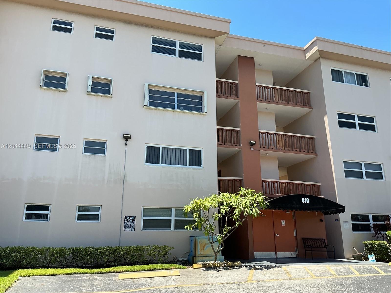 A multi-story apartment building exterior features a brown central entryway with balconies and beige walls — 410 SE 2nd St # 307, Hallandale Beach FL 33009, HALLANDALE BEACH, FL