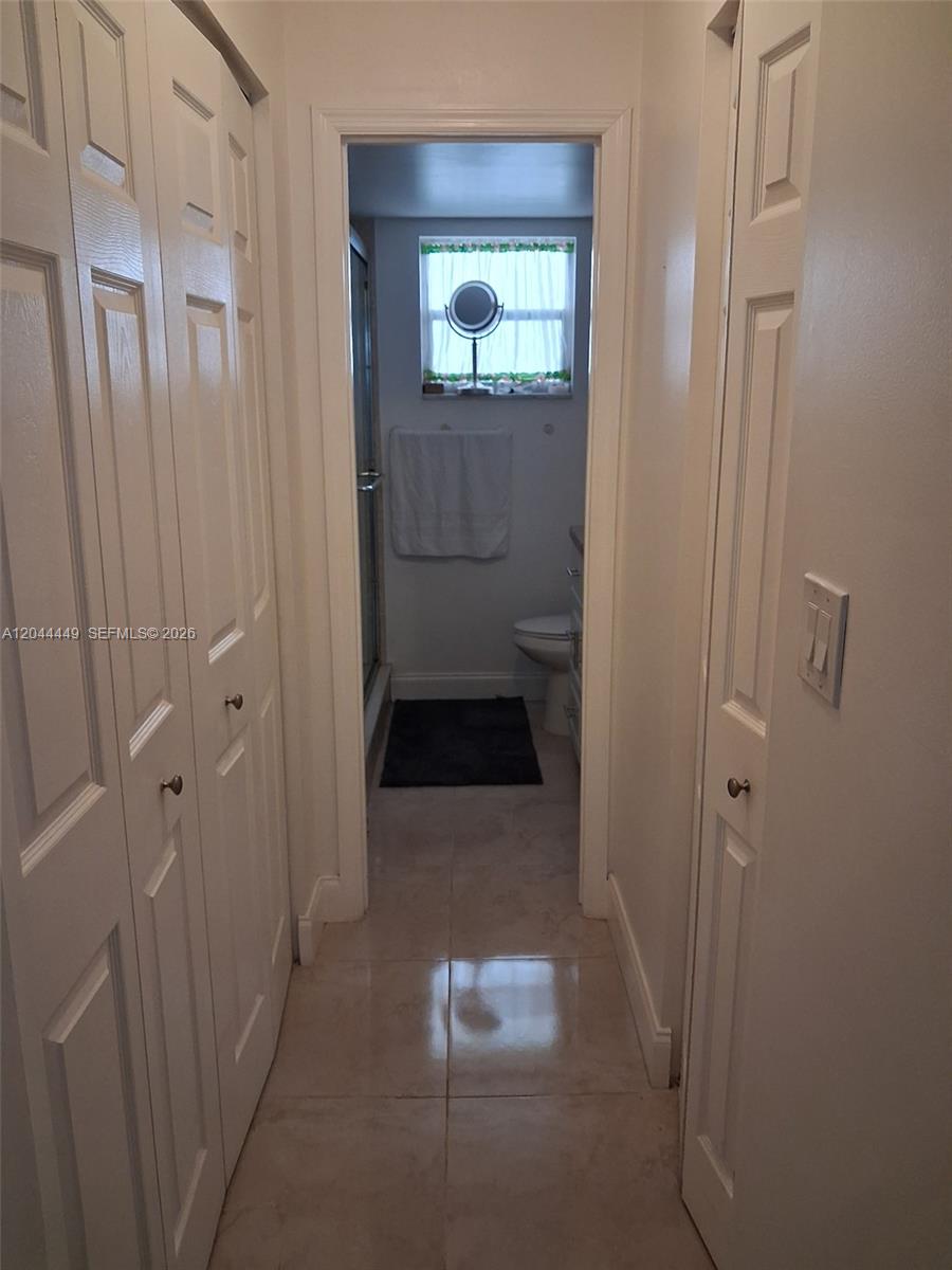 A narrow hallway with white paneled closet doors leads to a bathroom with tile flooring — 410 SE 2nd St # 307, Hallandale Beach FL 33009, HALLANDALE BEACH, FL