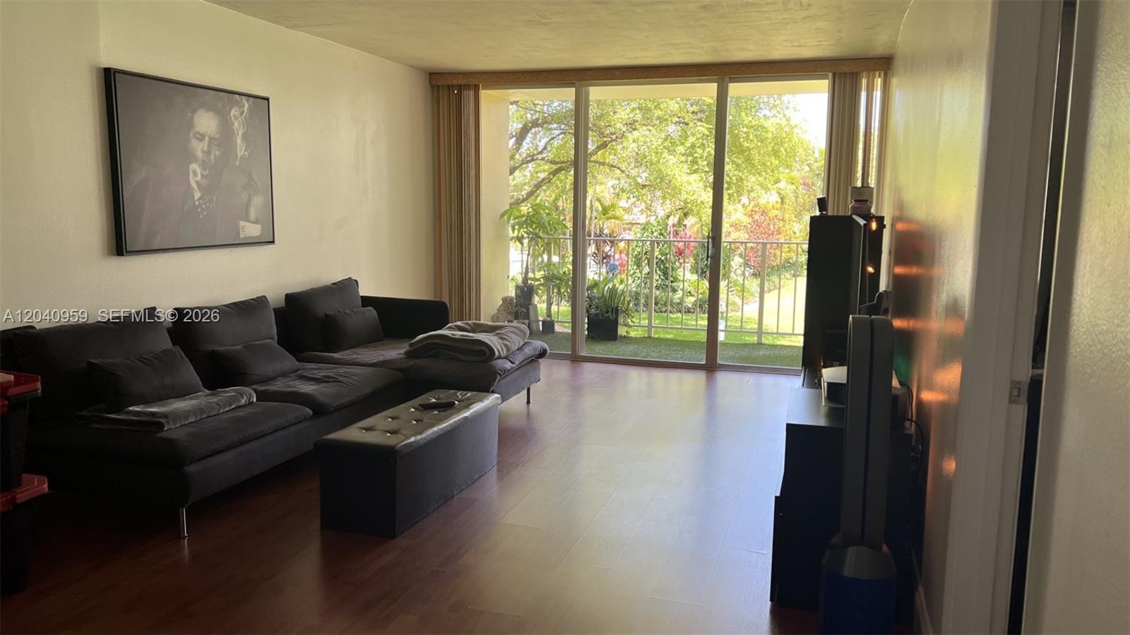 A living room features dark wood flooring, a sectional sofa, and a sliding glass door — 13120 SW 92nd Ave # 209, Miami FL 33176, MIAMI, FL