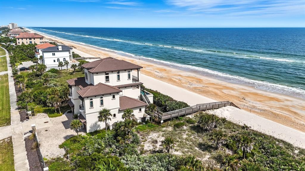 An aerial view shows a multi-story house on a beach with a private boardwalk — 3715 N OCEAN SHORE BOULEVARD, PALM COAST, FL