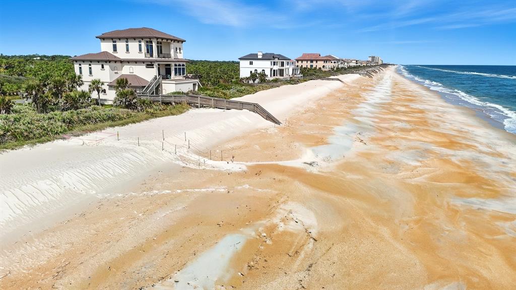 An aerial view shows a large beachfront house with a wooden walkway leading to the sand — 3715 N OCEAN SHORE BOULEVARD, PALM COAST, FL