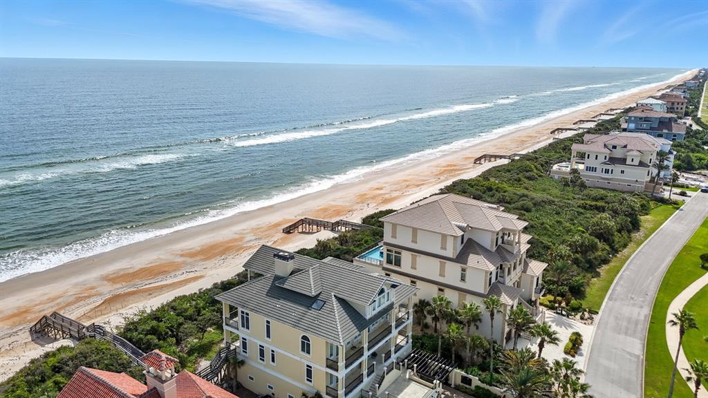 An aerial view shows several multi-story beachfront homes along a sandy coastline — 3715 N OCEAN SHORE BOULEVARD, PALM COAST, FL