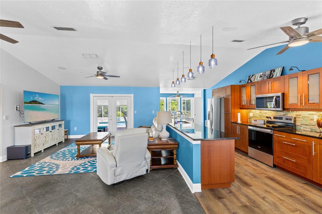 An open-concept living room and kitchen with blue walls, wood cabinets, and tile flooring — 3951 SANTA BARBARA ROAD, KISSIMMEE, FL