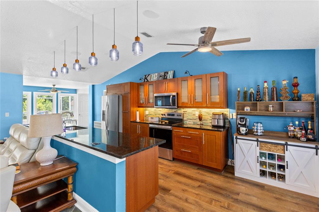 A kitchen with wood cabinets, blue walls, a breakfast bar, and a wine storage console — 3951 SANTA BARBARA ROAD, KISSIMMEE, FL