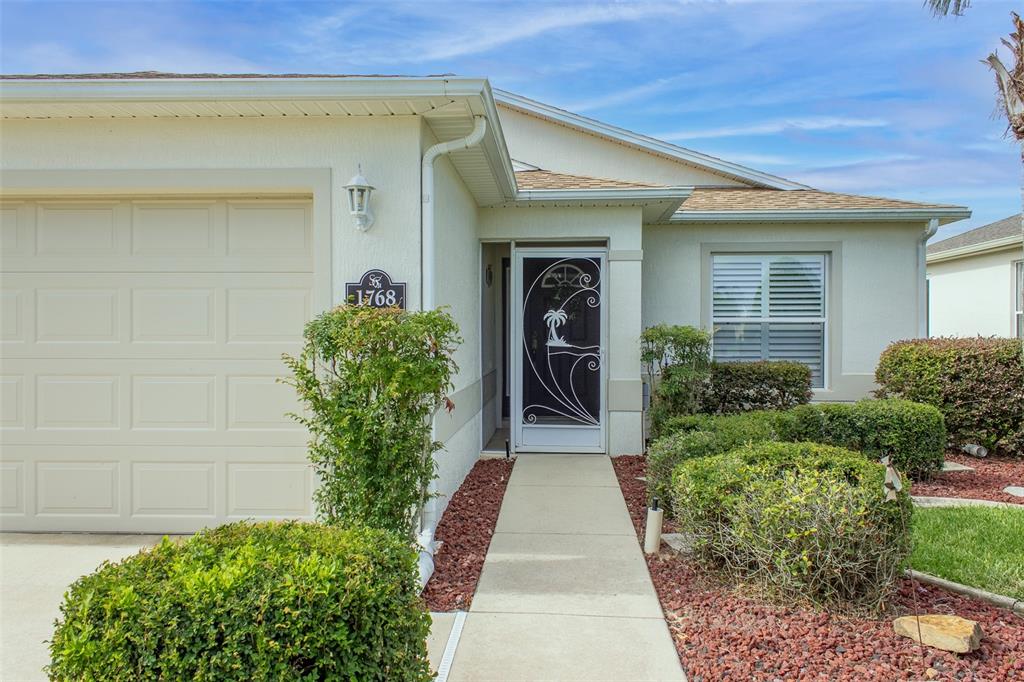 The exterior of a single-story house features a garage, a front walkway, and landscaping — 1768 SW 156TH LANE, OCALA, FL