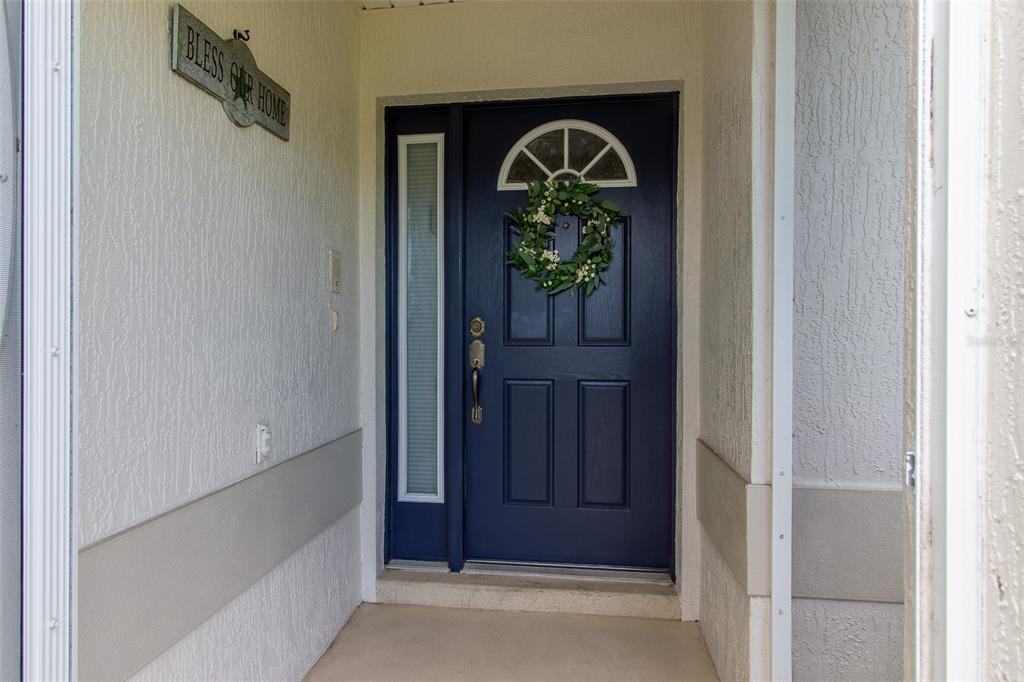 A blue front door with a wreath and a side light sits in a covered entryway — 1768 SW 156TH LANE, OCALA, FL