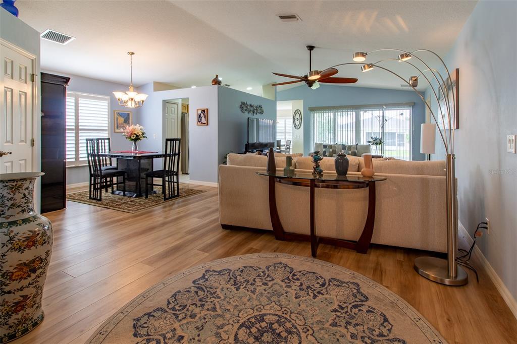 An open-concept living and dining area features light wood flooring, a sofa, and a rug — 1768 SW 156TH LANE, OCALA, FL