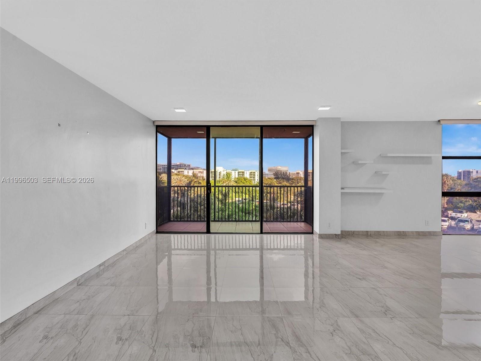 Spacious living area with natural light and balcony view — AVENTURA, FL