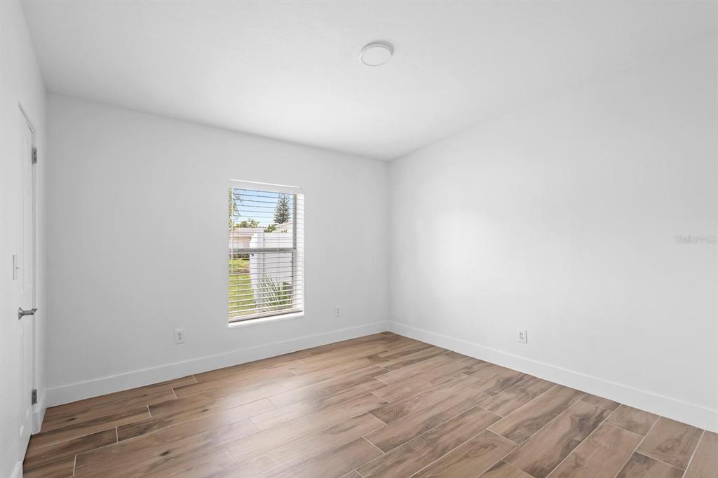 An empty bedroom features white walls, a single window, and wood-look tile flooring — 1511 E HORATIO AVENUE, MAITLAND, FL