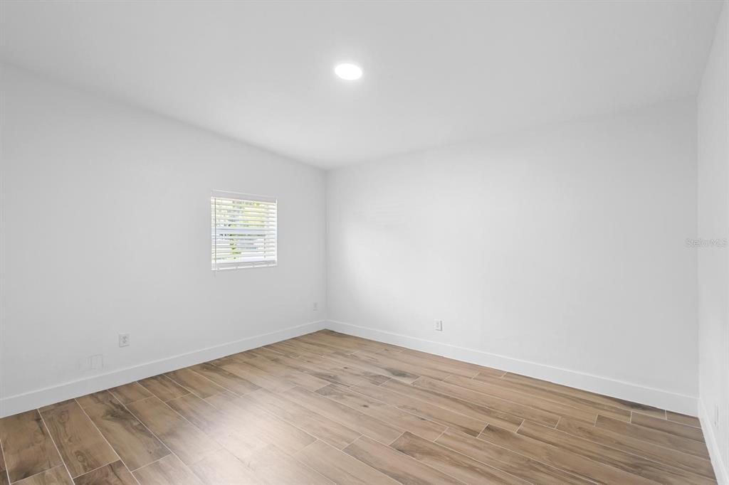An empty bedroom features white walls, a single window with blinds, and wood-look tile flooring — 1511 E HORATIO AVENUE, MAITLAND, FL